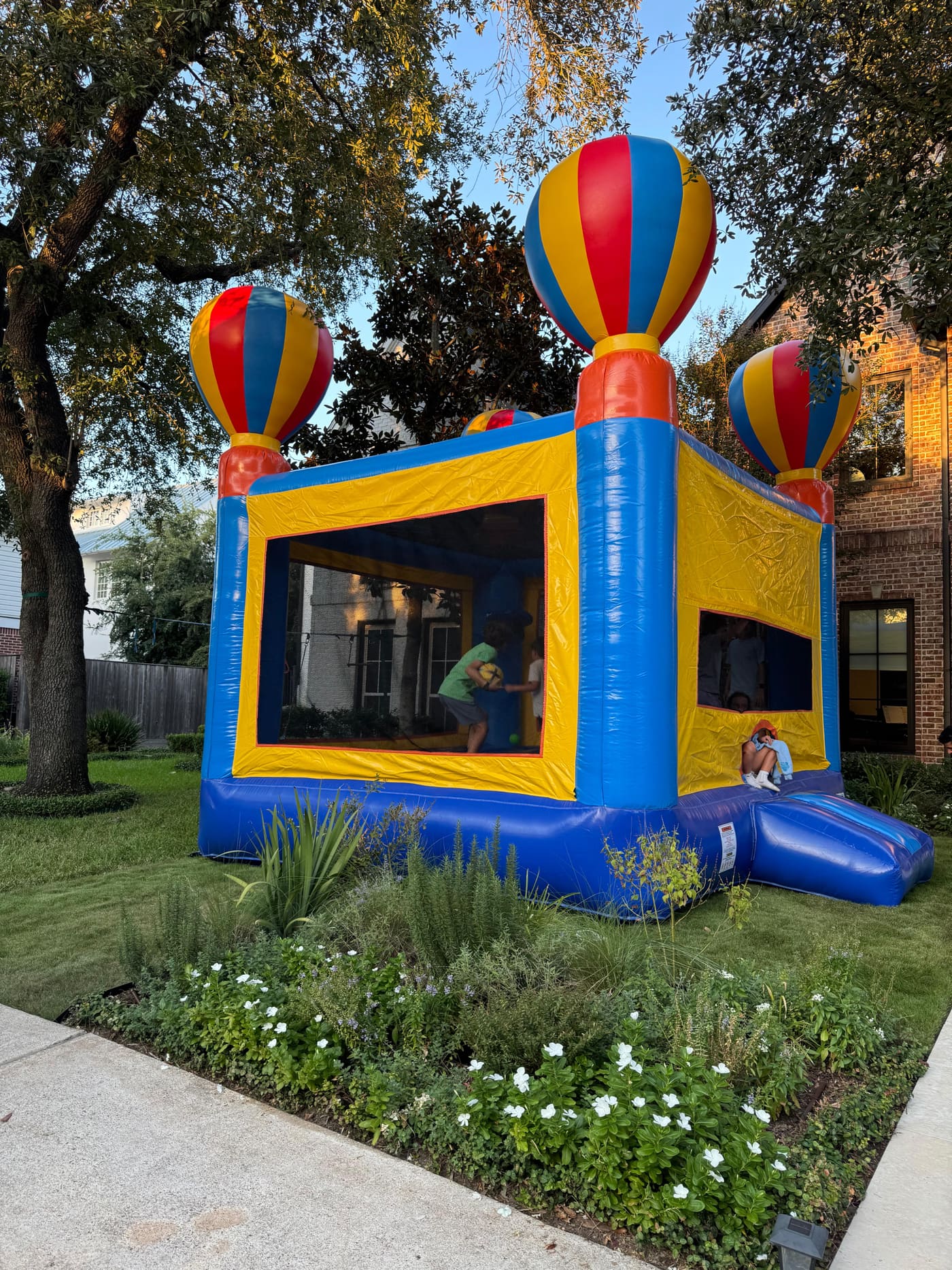 Children playing in the balloon bounce house beside a brick home